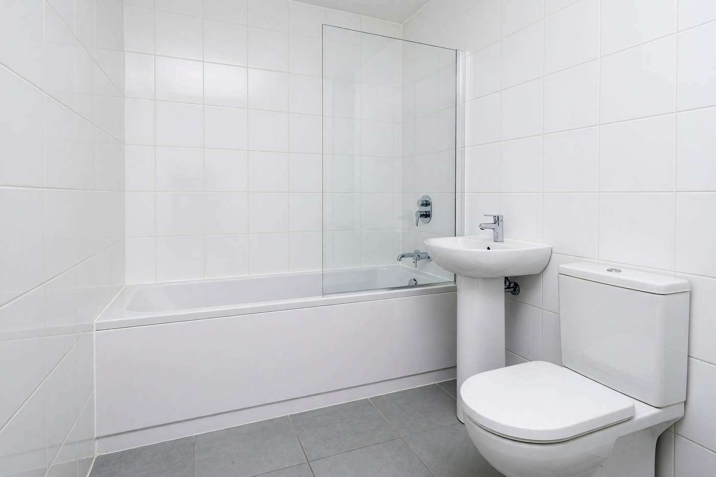 The same bathroom after a deep clean, white grout and a clear screen